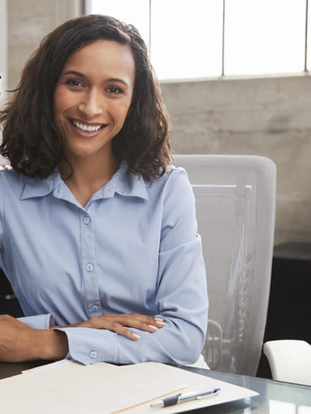 Young female professional at desk smiling to camera