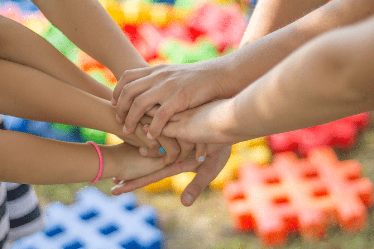 Mãos unidas, representando a união e solidariedade necessária para a educação inclusiva nas escolas.