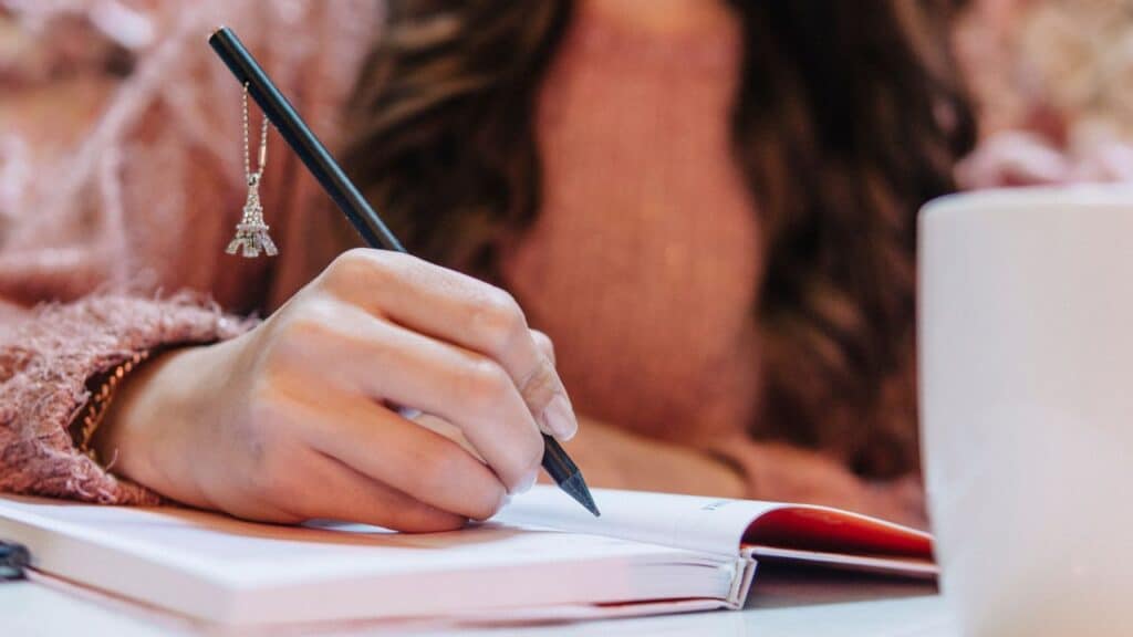 mulher escrevendo em um caderno 