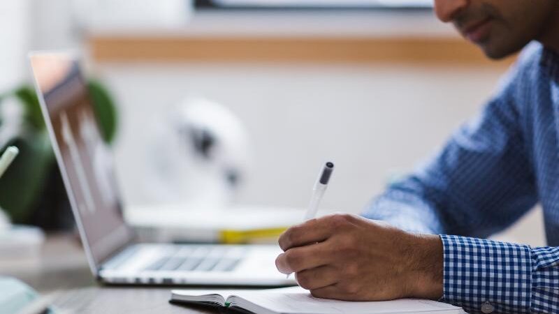 homem realizando pesquisa científica em uma mesa com libro e computador