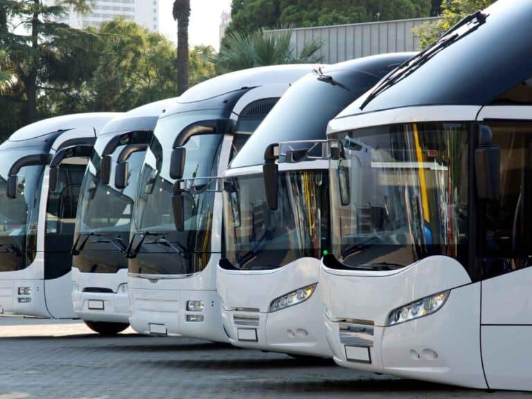 Grupo de ônibus estacionado em uma garagem lado a lado.